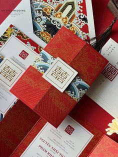 an assortment of red and gold wedding stationery on top of each other with flowers in the middle