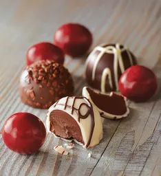 chocolates and cherries on a wooden table, with one half cut in half