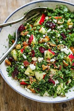 a white bowl filled with chopped vegetables on top of a wooden table next to a fork