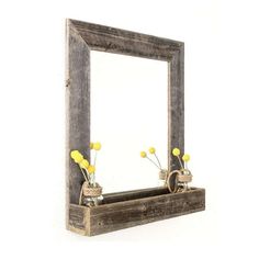 a wooden mirror frame with flowers in it on a shelf next to a white wall