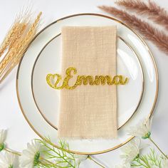 a white plate topped with a napkin covered in gold glitter name on top of it