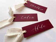 three red name tags with white ribbons on them