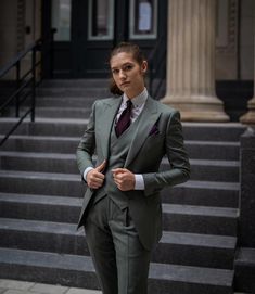 a woman wearing a suit and tie standing in front of steps with her hands on her hips