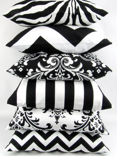 black and white pillows stacked on top of each other in front of a white background