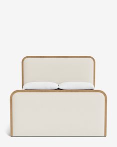 a bed with two pillows on top of it and a wooden frame around the headboard