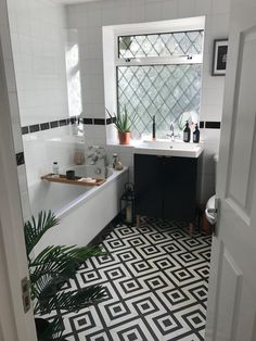 a bathroom with black and white tile flooring next to a bathtub in the corner