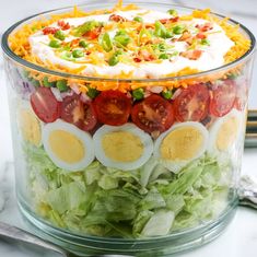 a salad with hard boiled eggs, tomatoes, lettuce and other toppings