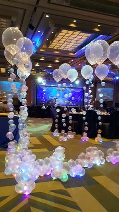 balloons are floating in the air at an event with tables and chairs set up behind them