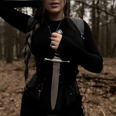 a woman holding a knife in the woods