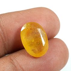 a close up of a person's finger holding a yellow gems