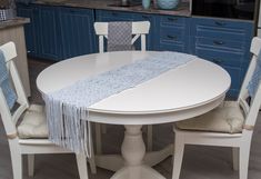 a white table and chairs in a room with blue cabinets on the wall behind them