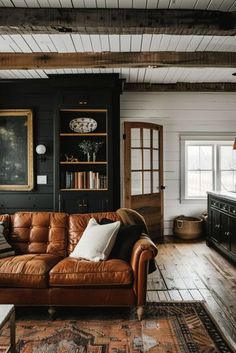 a brown leather couch sitting in a living room on top of a wooden floor