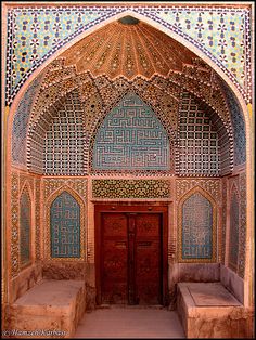 the inside of an ornate building with two benches in front of it and a wooden door