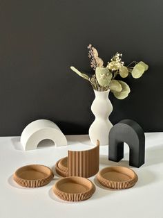 a white vase filled with flowers next to three black and white plates on a table