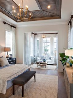 a bedroom with a large bed and chandelier hanging from it's ceiling