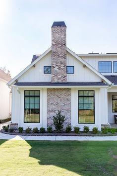 a white house with a brick chimney in the front yard