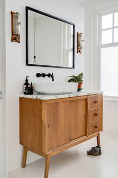 a bathroom with a sink, mirror and wooden cabinet