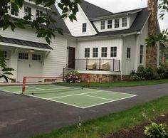 a tennis court in front of a large white house