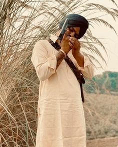 a man standing in the desert talking on a cell phone while holding a camera to his face