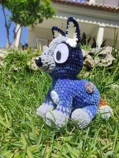 a blue and white stuffed animal sitting in the grass