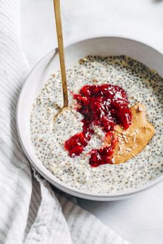 a bowl of oatmeal with berries and peanut butter in it on a white surface