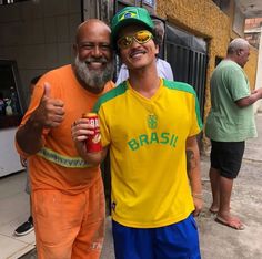 two men dressed in orange and green are posing for a photo while one holds up a can of beer