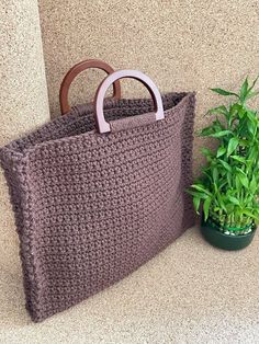 a crocheted bag sitting next to a potted plant on the side of a wall