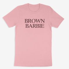 Be the definition of cool with this Brown Barbie Tee! It's unisex fit is perfect for all fans of Barbie, making you the envy of all your friends. Plus, with 3-7 business days for processing, you'll be ready to rock in no time! Band Merch Tops With Text Print, Band Merch Tops In Ring-spun Cotton With Text Print, Ring-spun Cotton Tops With Text Print, Band Merch Style, Ring-spun Cotton Tops With Text Print For Band Merch, Unisex Letter Print T-shirt In Pop Culture Style, Unisex Pop Culture T-shirt With Letter Print, Unisex Pre-shrunk Ring-spun Cotton T-shirt, Unisex T-shirt With Text Print For Fan Merchandise, Pop Culture Tops With Letter Print