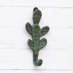 a green metal wall decoration on a white wooden background with the shape of a cactus