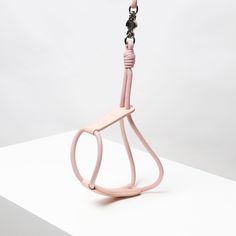 a pink object is hanging from a hook on a white surface with a gray background