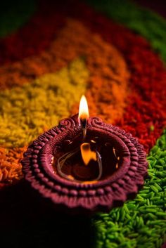 a small candle is lit in the middle of a rainbow colored carpet