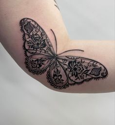 a black and white butterfly tattoo on the right arm, with intricate lacework work