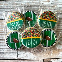 four decorated cookies in the shape of footballs with sprinkles on them