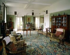 a living room filled with lots of furniture next to a window covered in curtains and drapes