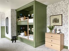 a green bunk bed in a room next to a dresser with drawers and pictures on the wall