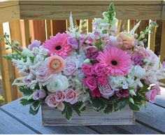 a wooden box filled with lots of pink and white flowers on top of a table