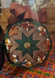 an ornament with bows on it sitting on top of a colorful table cloth