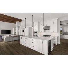 a large kitchen with white cabinets and wood floors