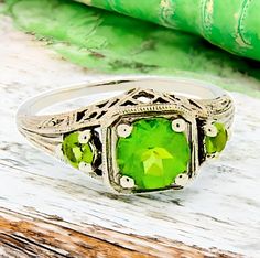 Discover the timeless elegance of our Vintage Estate Natural Peridot Three Stone Filigree Ring, crafted from luxurious 10K solid white gold that glimmers with sophistication. This exquisite piece, measuring 3/4 x 3/8 inches with 18x9 mm of intricately designed filigree, showcases three stunning natural peridot stones, radiating vibrant green hues that evoke the freshness of a summer garden. Each facet reflects light beautifully, creating a captivating sparkle that will not only adorn your hand but also capture the hearts of those around you. Perfect for both everyday wear or special occasions, this ring is stamped 10K and is in excellent condition, making it a truly exceptional addition to any jewelry collection. Don't miss your chance to own this enchanting piece--secure it today and let Luxury Faceted Peridot Jewelry, Luxury Three Stone Peridot Rings, Classic Peridot Birthstone Ring, Wedding Filigree Ring With May Birthstone, Green Filigree Ring For Anniversary, Green Filigree Ring Hallmarked For Anniversary, Green Filigree Hallmarked Ring For Anniversary, Classic Peridot Birthstone Ring For Formal Occasions, Classic Formal Peridot Birthstone Ring