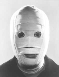 a person wearing a white mask with one eye open and the other half covered up