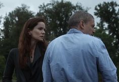 a man and woman are walking in the rain together, one is wearing a blue shirt