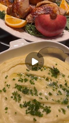 a bowl of mashed potatoes with garnishes and meat in the background