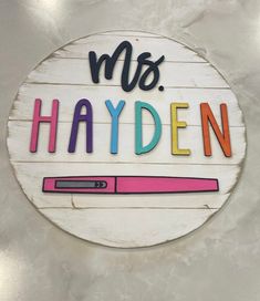 a wooden sign that says, mrs hayden with a pen on it and the words'ms hayden'in multi - colored letters