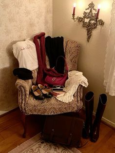 a chair with shoes, purses and other items on it in front of a chandelier