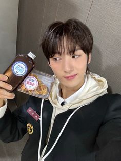 a young man is holding up a bottle of coffee and some food in front of him