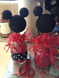 mason jars with mickey mouse heads and red ribbon tied around them, sitting on a table