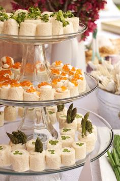 three tiered trays filled with food on top of a table next to flowers