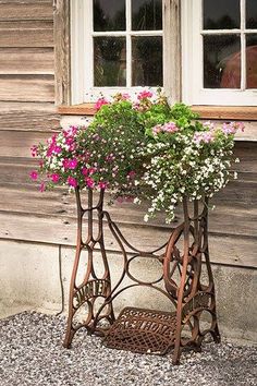 a metal planter with flowers in it next to a wooden wall and window sill