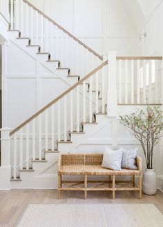 a wooden bench sitting under a stair case next to a banister in a living room