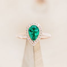 a ring with a heart shaped emerald surrounded by diamonds